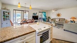 A modern kitchen with granite countertops, a built-in oven, and a dining area with wooden chairs. - Frisco Coastal Paradise w/ Boat Dock & Water Views (Frisco)