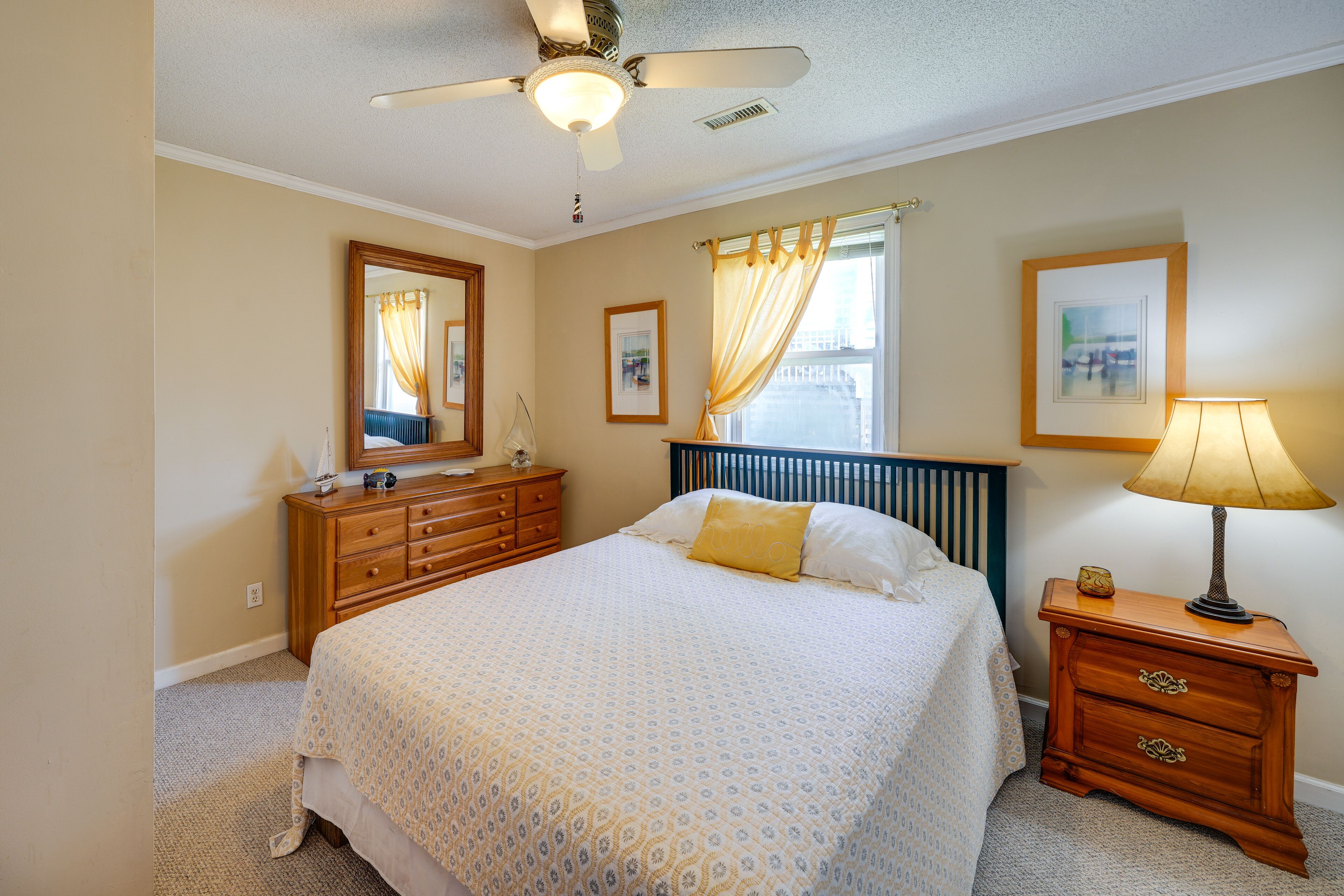 A bedroom with a bed, dresser, nightstand, and ceiling fan.