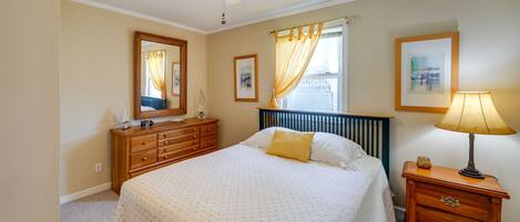 A bedroom with a bed, dresser, nightstand, and ceiling fan.