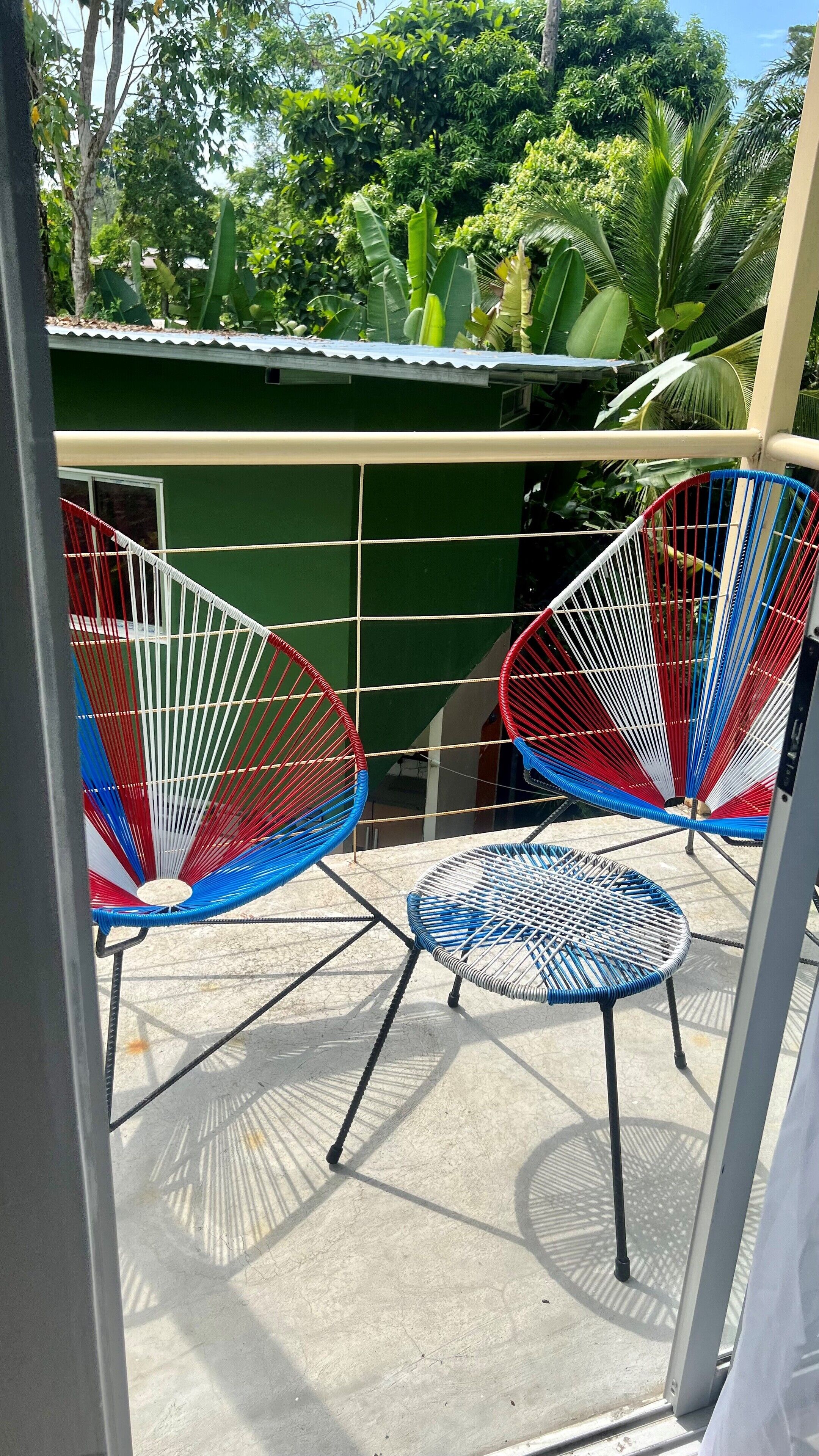 A balcony with two colorful hammocks and a small round table.