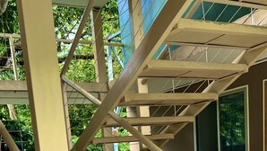 A concrete staircase with metal railings and a handrail, leading to a window with a view of greenery.
