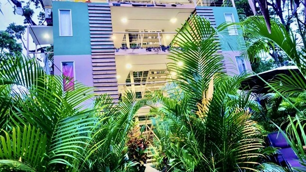 A multi-level building with a central atrium surrounded by lush greenery.