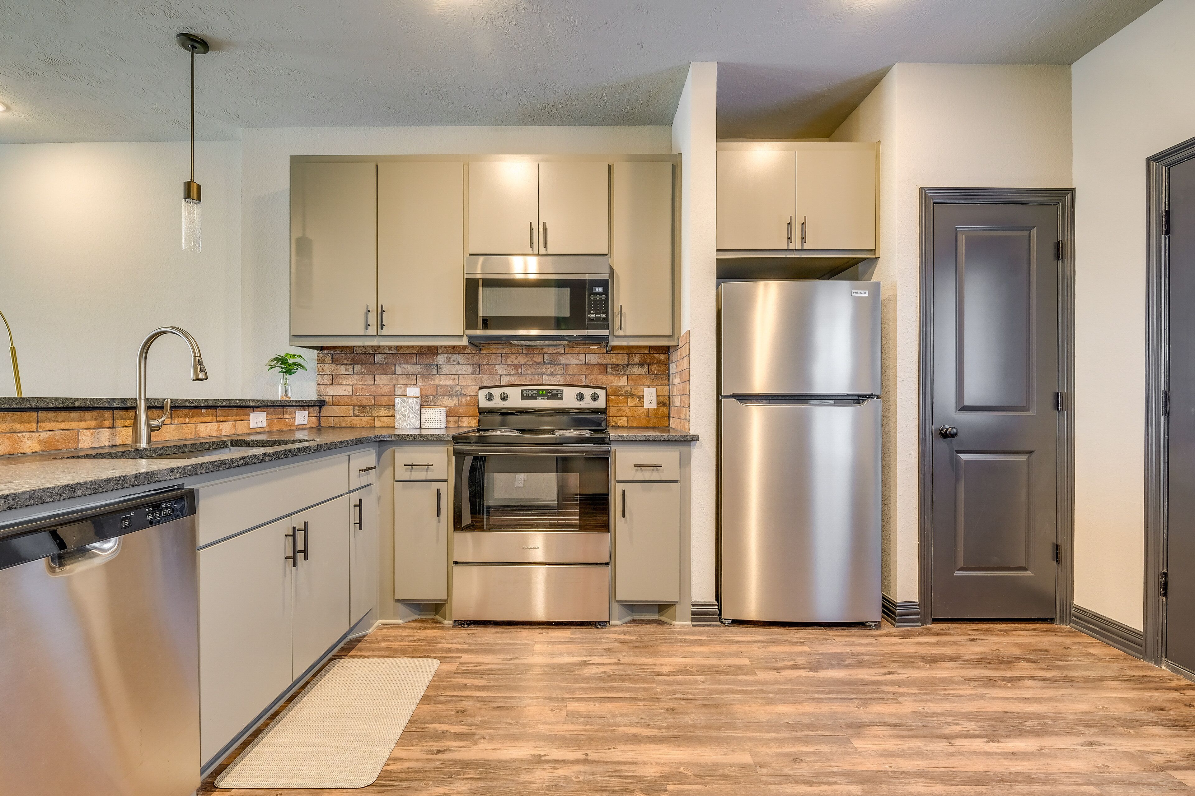 Una cocina moderna con electrodomésticos de acero inoxidable, armarios de colores claros y piso de madera.