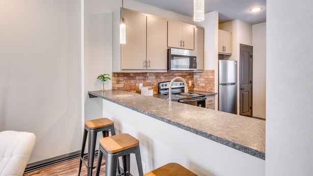 A modern kitchen with a granite countertop, stainless steel appliances, and a brick backsplash. - 'Corner Hideaway' 3 Mi to Texas A & M (College Station)