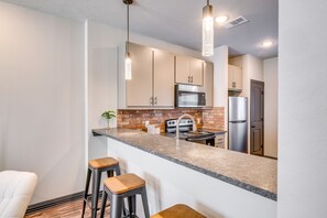 A modern kitchen with a granite countertop, stainless steel appliances, and a brick backsplash. - Newly Built 'Corner Hideaway' 3 Mi to Texas A & M (College Station)