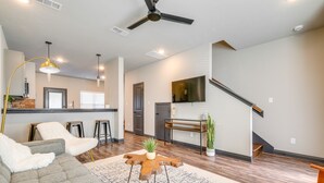 A modern living room with a sectional sofa, a wooden coffee table, and a staircase leading to an upper level. - 'Corner Hideaway' 3 Mi to Texas A & M (College Station)