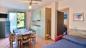 A compact living space with a dining area, kitchenette, and a bed. - Apartment SMERALDO 3 (manerba del garda solarolo)