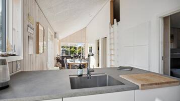 Une cuisine moderne dotée d’un grand îlot central, d’un évier en acier inoxydable et d’une planche à découper en bois.