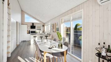 Une cuisine moderne avec des meubles blancs, un îlot central et un coin repas comprenant une table ronde et des chaises.