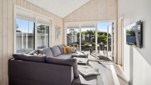 A modern living room with a grey sofa, a small table, and a TV mounted on the wall. - Lovely home in Sjølund (Sjølund)