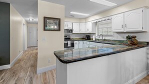 A modern kitchen with white cabinetry, a granite countertop, and a built-in oven. - Riverfront Cabin, Private 2 Tier Dock, Ichetucknee (Fort White)