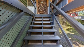 A staircase with a geometric design leading to a door, surrounded by wooden beams and a lattice structure. - Riverfront Cabin, Private 2 Tier Dock, Ichetucknee (Fort White)