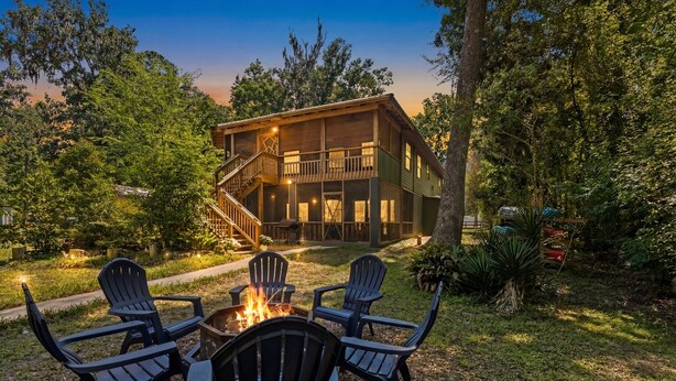 A wooden cabin with a fire pit and chairs in the yard, surrounded by trees. - Riverfront Cabin, Private 2 Tier Dock, Ichetucknee (Fort White)