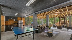 A spacious indoor area with a ping pong table, a kitchen with modern appliances, and a seating area with a view of the outdoors. - Riverfront Cabin, Private 2 Tier Dock, Ichetucknee (Fort White)