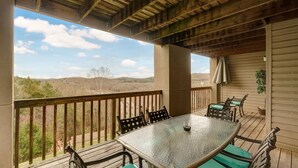 A covered outdoor patio with a table and chairs, overlooking a scenic landscape.