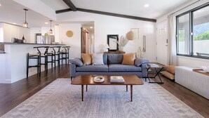 A spacious living area with a sofa, coffee table, and a view of the outdoors through large windows.