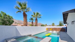 A swimming pool with clear water, surrounded by white walls and palm trees.