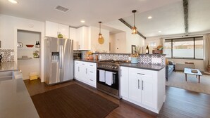 A modern kitchen with white cabinets, stainless steel appliances, and a brown rug.