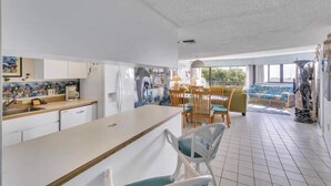 A compact kitchen with a dining area, a view through a large window, and a statue in the corner. - Beautiful Key Largo Condo with Direct Ocean Views (Key Largo)