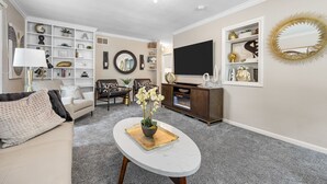 Un salon comprenant un canapé, une table basse, un téléviseur et des étagères décoratives.