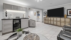 Une cuisine moderne avec des meubles gris, un four encastré et un coin repas comprenant une table et des chaises en marbre.