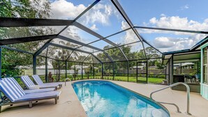 A swimming pool with lounge chairs, a metal roof structure, and a view of the surrounding area. - Heated Private Pool, 5 Miles to Beach. Colorful, bright family-sized home.  (Vero Beach)