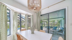 A dining area with a white table, wicker chairs, and a decorative vase. - Heated Private Pool, 5 Miles to Beach. Colorful, bright family-sized home.  (Vero Beach)