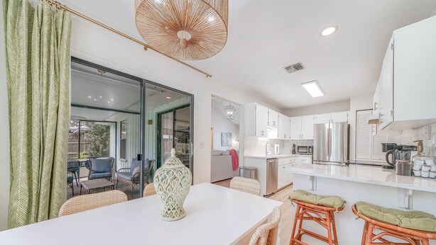 A modern kitchen with white cabinets, stainless steel appliances, and a large island with stools. - Heated Private Pool, 5 Miles to Beach. Colorful, bright family-sized home.  (Vero Beach)