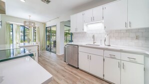 A modern kitchen with white cabinets, a stainless steel dishwasher, and a glass-top island. - Heated Private Pool, 5 Miles to Beach. Colorful, bright family-sized home.  (Vero Beach)
