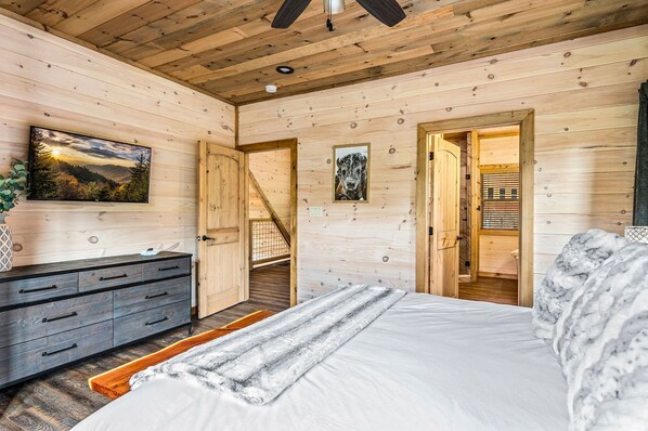Een houten slaapkamer met een bed, een dressoir en een landschapsschilderij.