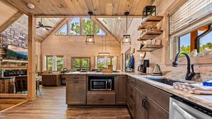 A spacious kitchen with wooden beams, a large island, and a stone fireplace. - Top 5% · Pet Friendly · Hot Tub · Arcade · Views (Sevierville)