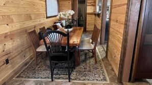 Un intérieur en bois comprenant une table à manger, des chaises et un ventilateur de plafond.