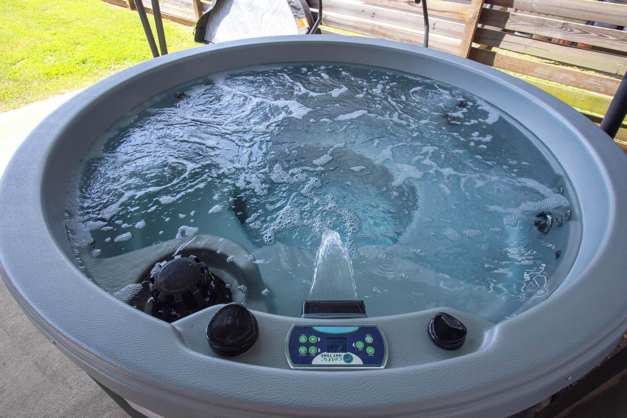 A hot tub with a control panel, surrounded by a wooden deck.