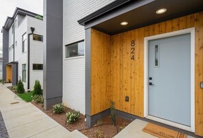 A modern building with a grey facade, a wooden door with the number 824, and a welcome mat at the entrance. - Rooftop Fire Pit & Cocktail Bar | Sleeps 12 | (Nashville)
