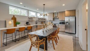 A modern kitchen with a central island, bar stools, and a large refrigerator. - Rooftop Fire Pit ~ Bach Parties ~ Sleeps 24! (Nashville)
