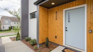 A modern building with a wooden front door labeled "828" and a "WELCOME" mat. - Rooftop Fire Pit ~ Bach Parties ~ Sleeps 24! (Nashville)