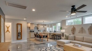 A spacious living area with a kitchen, dining table, and a large window providing natural light. - Rooftop Fire Pit ~ Bach Parties ~ Sleeps 24! (Nashville)