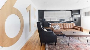 A modern living room with a large sofa, a coffee table, and a TV. - Rooftop Lounge ~ Sleeps 12 ~4 bed (Nashville)