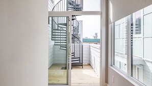 A narrow hallway with wooden flooring leading to a glass door opening to a balcony with a spiral staircase. - ~ Rooftop lounge ~ 4 bed ~ Sleeps 10! (Nashville)