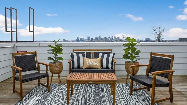 A rooftop patio with a city skyline view, featuring a wooden table, two chairs, a sofa, and potted plants. - ~ Rooftop lounge ~ 4 bed ~ Sleeps 10! (Nashville)