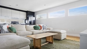 A modern living room with a sectional sofa, a wooden coffee table, and a kitchen area in the background. - ~ Rooftop lounge ~ 4 bed ~ Sleeps 10! (Nashville)