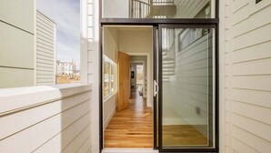 A narrow hallway with a wooden floor leading to a glass door. - ~ Rooftop lounge ~ 4 bed ~ Sleeps 10! (Nashville)