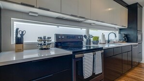 A modern kitchen with a built-in oven, a stovetop, and a window above the sink.