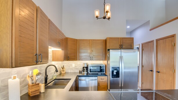 A modern kitchen with wooden cabinets, stainless steel appliances, and a black countertop. - 6 Mi to Winter Park: Mtn-View Condo w/ Balcony! (Fraser)