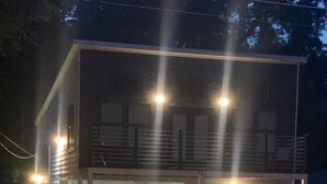 Ein zweigeschossiges Haus mit überdachter Veranda, einer Garage und einem kleinen Balkon.
