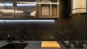 A modern kitchen with dark marble countertops, a wooden cutting board, a gas stove, and stainless steel appliances. - 10 Minutes From Ipanema Beach Vm201 (Rio de Janeiro)