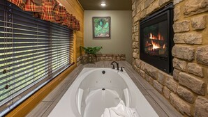 Ein Badezimmer mit einer großen Badewanne, einem Kamin und einem Fenster mit Jalousien.