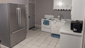 A compact kitchen with a stainless steel refrigerator, a white stove, and a sink. - 2BR Apt Right on the Town Square (Robinson)