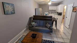 A compact living space with a sofa, coffee table, and a kitchenette area. - 2BR Apt Right on the Town Square (Robinson)