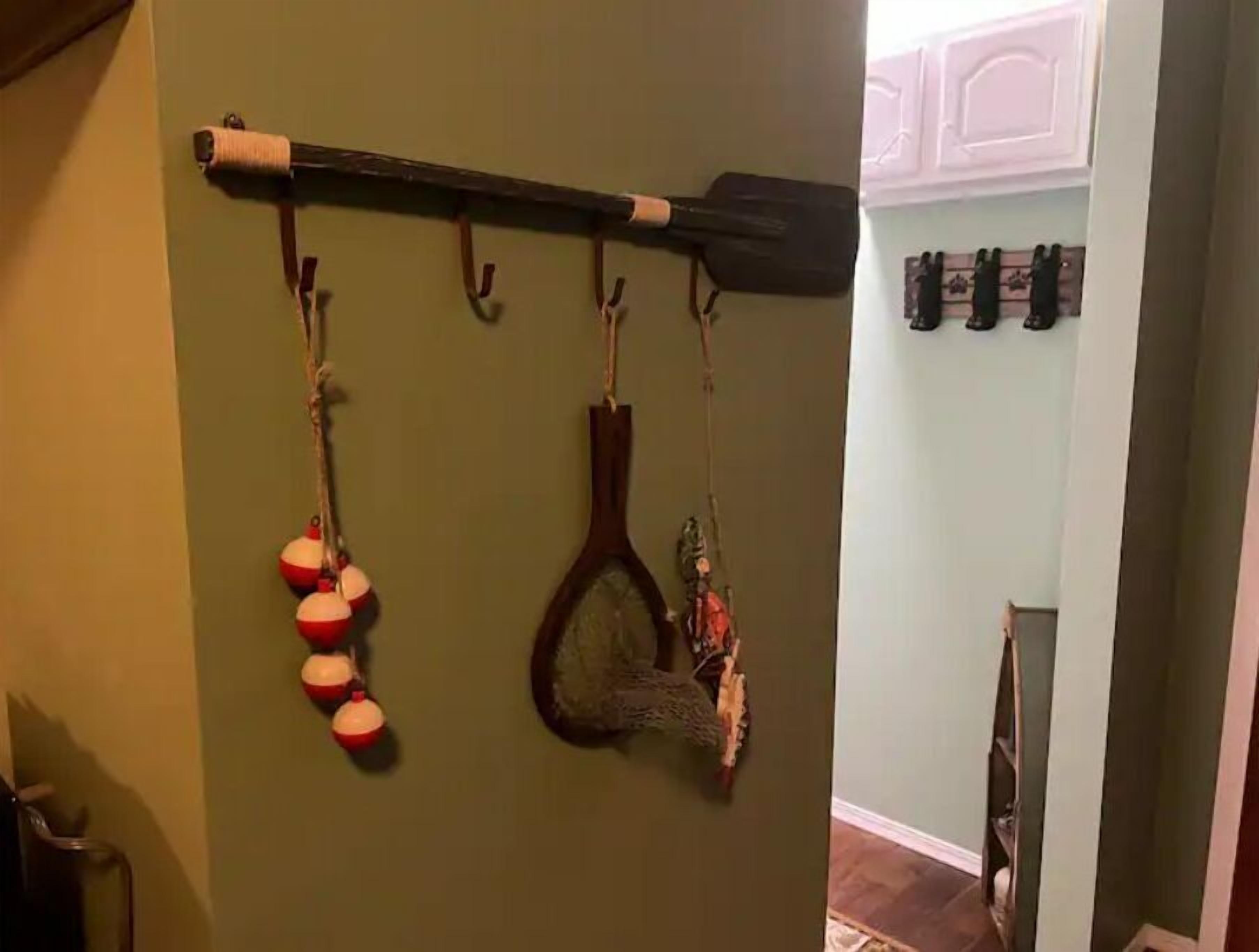 Ein Flur mit einem an der Wand befestigten Gestell, das einen Paddel, ein Fischernetz und mehrere rot-weiße Bälle enthält.